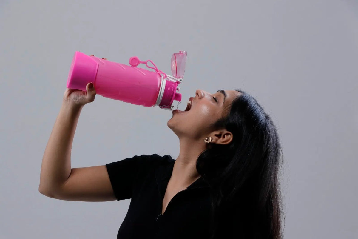 A woman squeezes a magenta Fllexibott and drinks